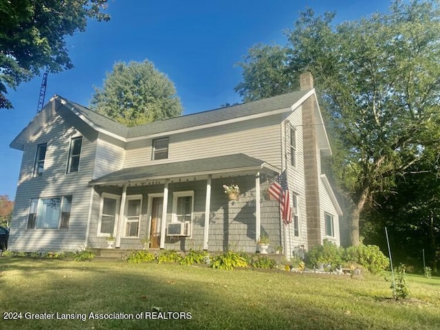 view of front of property featuring a front lawn, covered porch, and a chimney