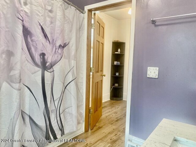 bathroom featuring baseboards, wood finished floors, and ornamental molding