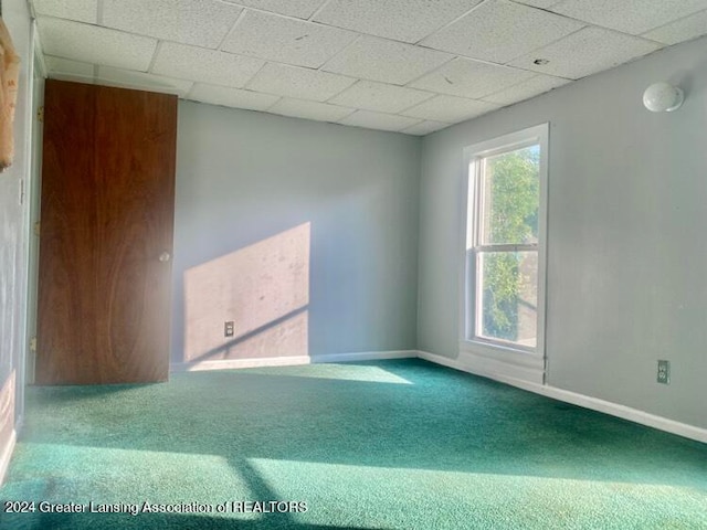 carpeted spare room with a paneled ceiling