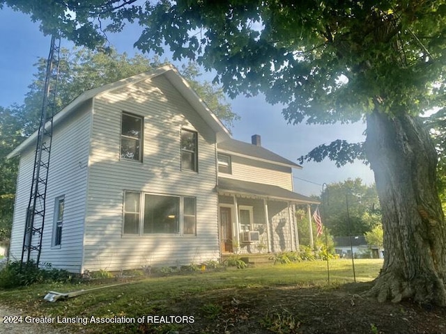 exterior space with a lawn, a chimney, cooling unit, and covered porch