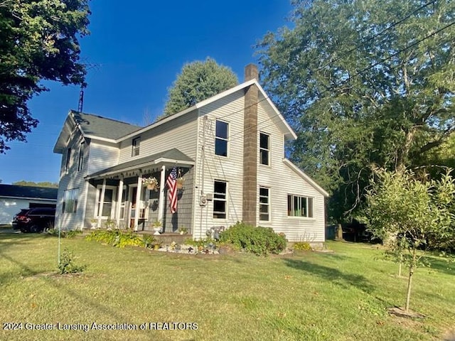 view of front facade with a chimney, covered porch, and a front yard