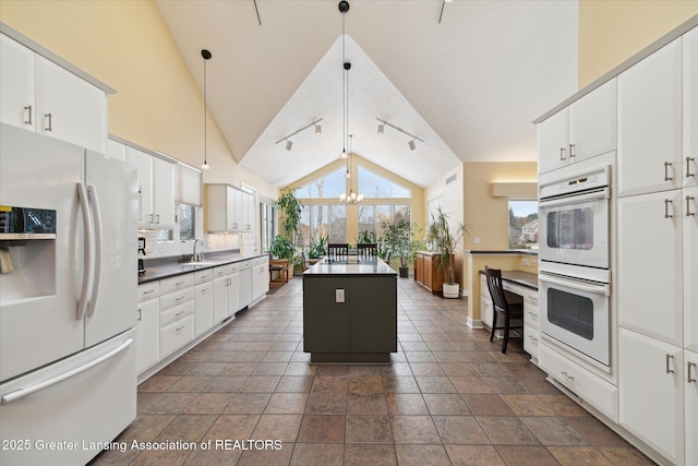 kitchen with hanging light fixtures, white cabinetry, a center island, and white appliances