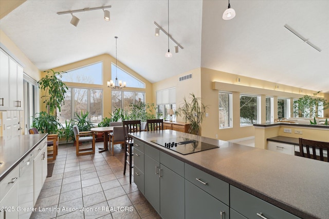 kitchen featuring black electric stovetop, decorative light fixtures, and white cabinets