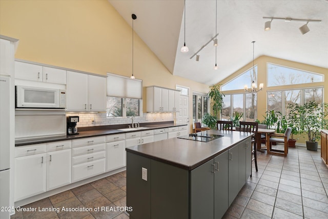 kitchen with sink, a center island, white cabinets, black electric cooktop, and decorative light fixtures