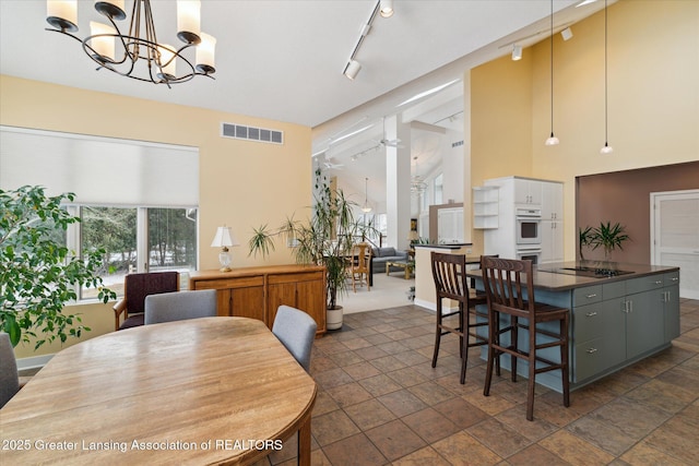 dining area featuring an inviting chandelier, track lighting, and high vaulted ceiling