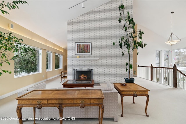 carpeted living room featuring a fireplace, high vaulted ceiling, and rail lighting