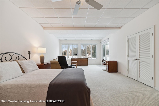 carpeted bedroom featuring ceiling fan, a paneled ceiling, and a closet