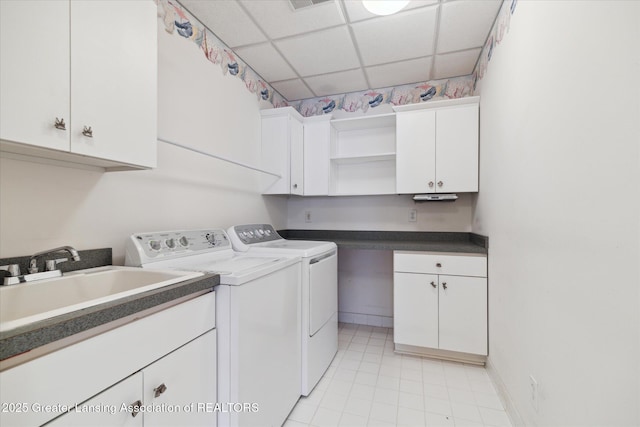 clothes washing area featuring sink, washer and clothes dryer, and cabinets