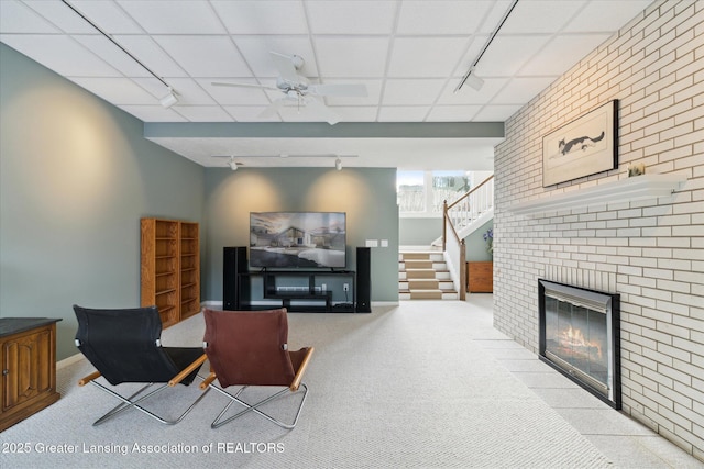 carpeted living room featuring a drop ceiling, a fireplace, ceiling fan, and track lighting