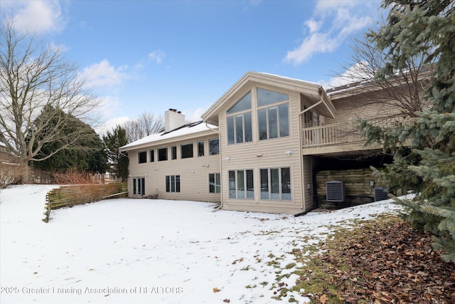 snow covered rear of property featuring central air condition unit