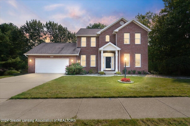 colonial inspired home featuring a lawn and a garage