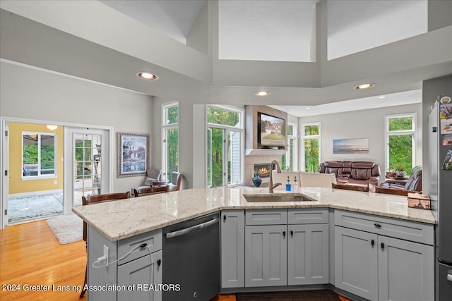 kitchen with a healthy amount of sunlight, a large fireplace, dishwasher, and sink