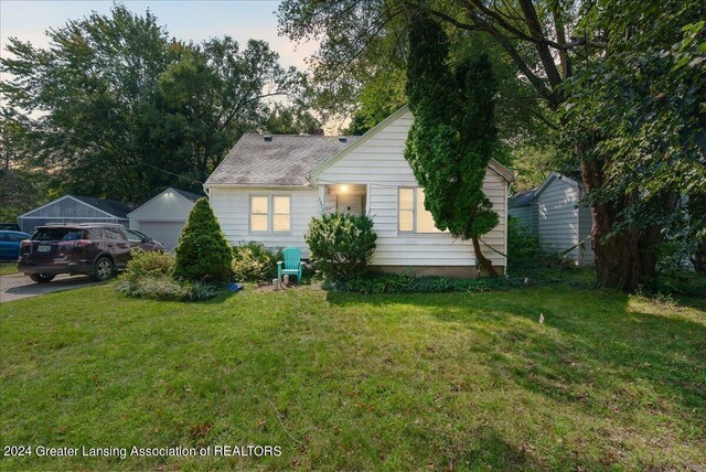 view of front of house featuring a front lawn and an outbuilding