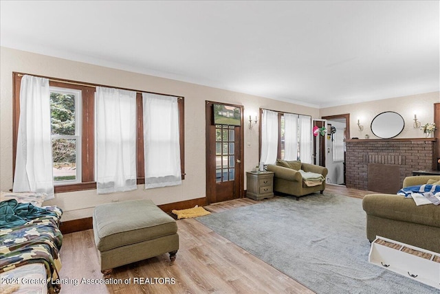 living room with a brick fireplace and light hardwood / wood-style floors