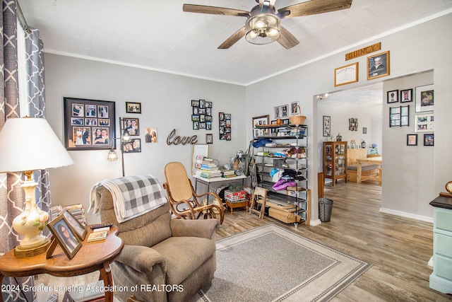 living area with ceiling fan, ornamental molding, and wood-type flooring