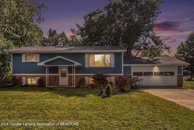 bi-level home featuring a garage and a lawn