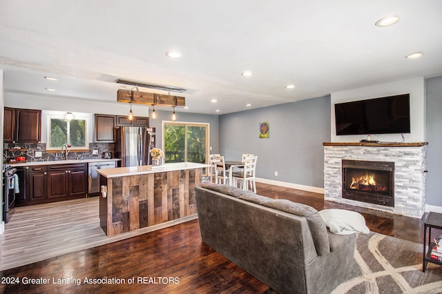 living room featuring hardwood / wood-style floors, a stone fireplace, and sink