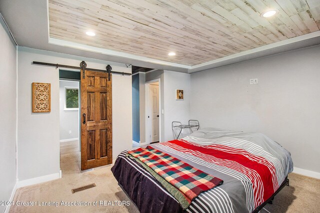 carpeted bedroom with a barn door and wooden ceiling