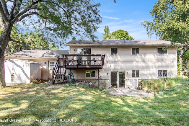 back of property featuring a storage unit, a lawn, a wooden deck, and a patio