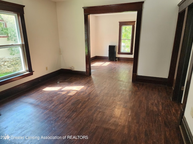 spare room featuring radiator and dark wood-type flooring