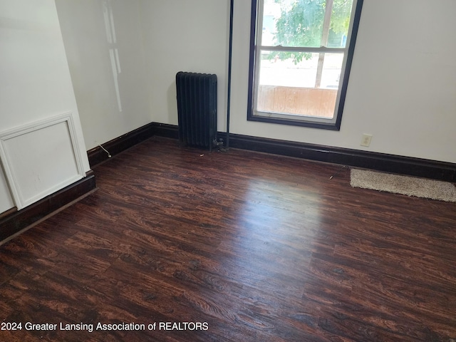 spare room with radiator heating unit and dark wood-type flooring