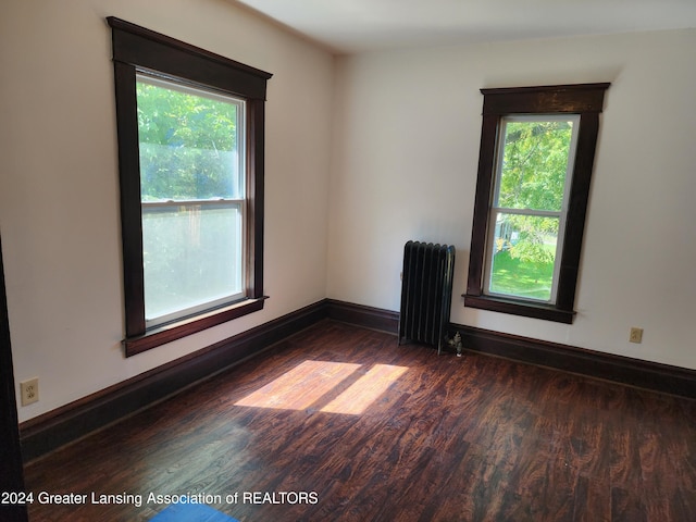 empty room with radiator, dark hardwood / wood-style flooring, and plenty of natural light