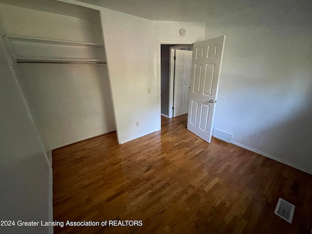 unfurnished bedroom featuring dark wood-type flooring and a closet