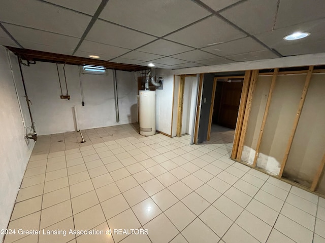 basement featuring gas water heater, a paneled ceiling, and light tile patterned floors