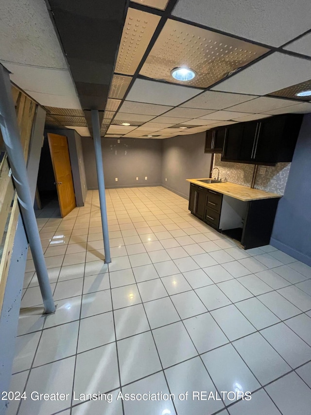 interior space with light tile patterned flooring, a drop ceiling, and sink