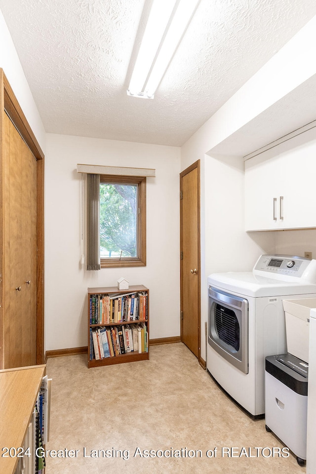 laundry room featuring a textured ceiling, washing machine and clothes dryer, light colored carpet, and cabinets