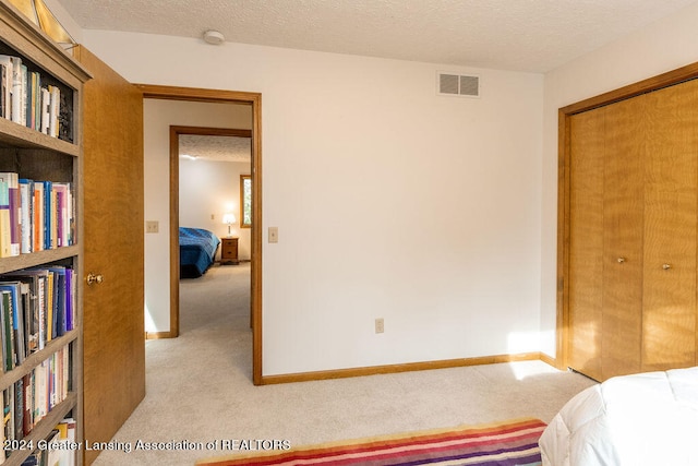 carpeted bedroom featuring a textured ceiling and a closet