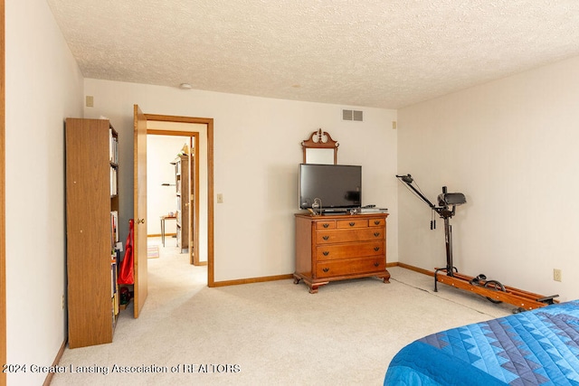 bedroom with light colored carpet and a textured ceiling