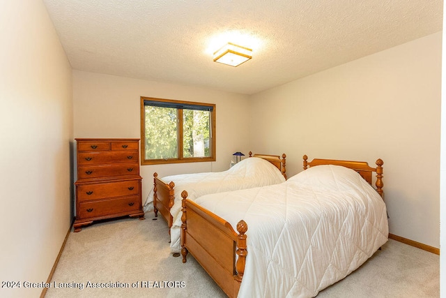 bedroom featuring a textured ceiling and light colored carpet