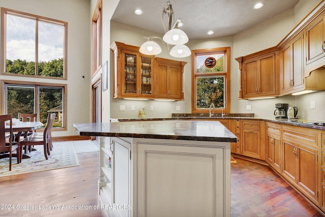 kitchen with a kitchen island, pendant lighting, a textured ceiling, light wood-type flooring, and sink