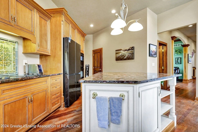 kitchen featuring black fridge, a kitchen island, decorative light fixtures, dark wood-type flooring, and an inviting chandelier