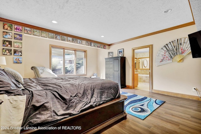 bedroom with ornamental molding, light wood-type flooring, a textured ceiling, and ensuite bathroom