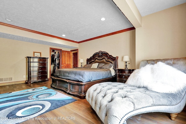 bedroom featuring a textured ceiling, wood-type flooring, a spacious closet, and a closet