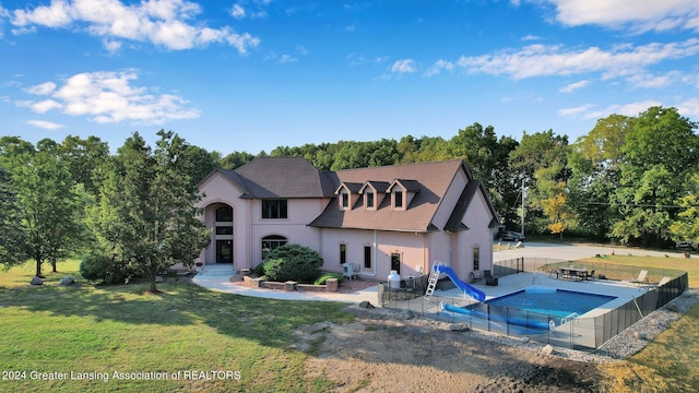 rear view of property with a covered pool, a patio area, and a yard