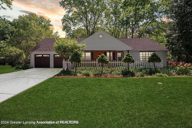 ranch-style home with a garage and a lawn