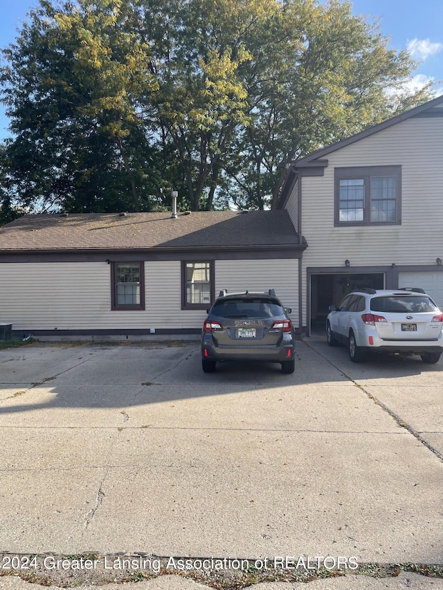 view of front of home featuring driveway, a garage, and roof with shingles