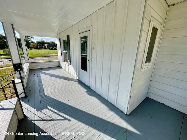 wooden terrace featuring covered porch and a yard