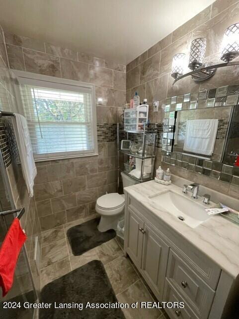 bathroom with backsplash, vanity, toilet, and tile walls