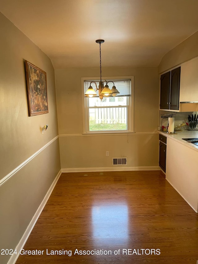 unfurnished dining area featuring dark hardwood / wood-style flooring and a chandelier