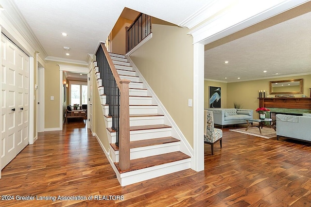 staircase featuring a textured ceiling, hardwood / wood-style floors, and crown molding