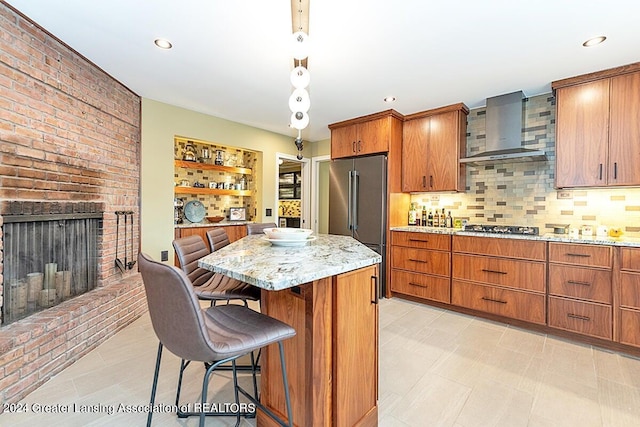 kitchen with appliances with stainless steel finishes, decorative backsplash, a kitchen breakfast bar, a kitchen island, and wall chimney range hood