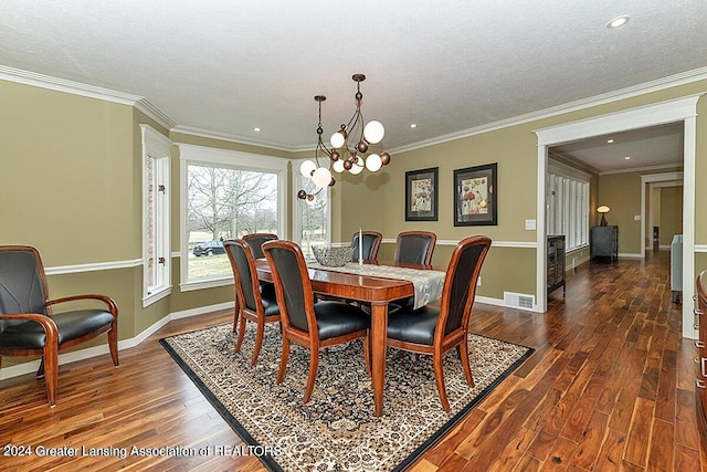 dining space with a textured ceiling, ornamental molding, dark wood-type flooring, and a notable chandelier