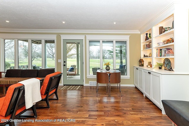 interior space with a textured ceiling, ornamental molding, and dark wood-type flooring