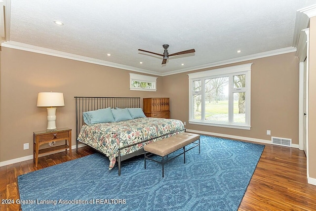 bedroom with ceiling fan, a textured ceiling, dark hardwood / wood-style floors, and crown molding