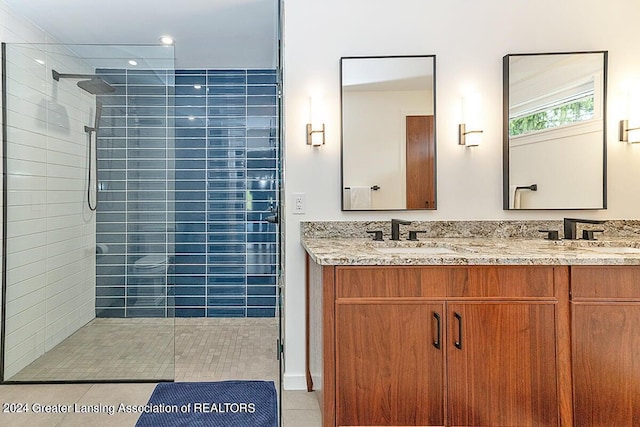 bathroom featuring a tile shower, tile patterned flooring, and vanity