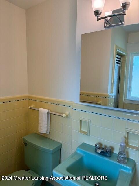 bathroom featuring tile walls, toilet, and sink